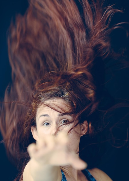Foto close-up portret van een vrouw met losgeknipt haar die tegen een zwarte achtergrond gebaren maakt