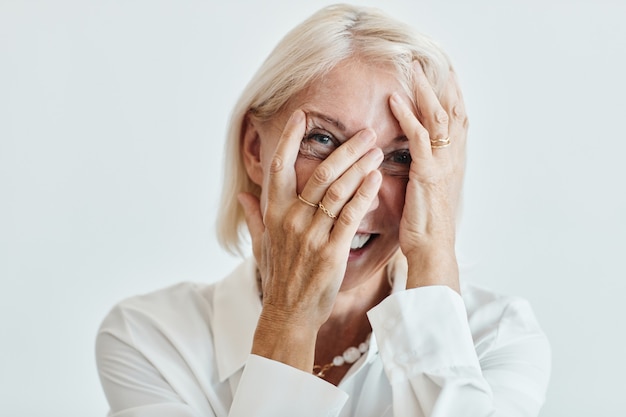 Close-up portret van elegante rijpe vrouw zorgeloos lachen tegen een witte achtergrond, kopieer ruimte