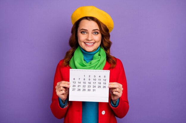 Close-up portret van haar mooie aantrekkelijke mooie mooie charmante vrolijke vrolijke golvende haren meisje in handen houden papieren kalender geïsoleerd op violet lila paarse pastel kleur achtergrond