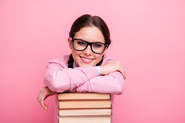 Close-up portret van haar ze aardig aantrekkelijk vrij vrolijk genie bruinharige tienermeisje genieten van hand in hand leunend op stapel boek wetenschap onderzoek geïsoleerde roze pastel kleur achtergrond