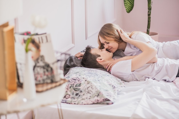 Close-up portret van jonge aantrekkelijke romantische paar knuffelen en zoenen, liggend op een bed, liefdevol met elkaar. Liefde en relaties levensstijl, interieur slaapkamer.