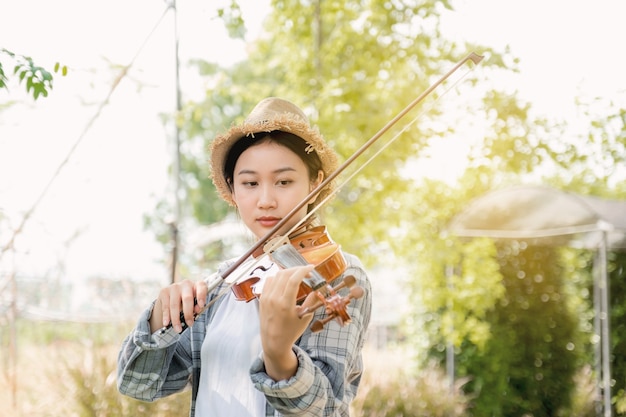 Close-up portret van jonge azië vrouw muziek violist viool spelen ontspannen in de tuin