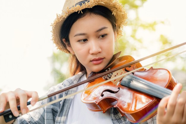 close-up portret van jonge azië vrouw muziek violist viool spelen ontspannen in de tuin