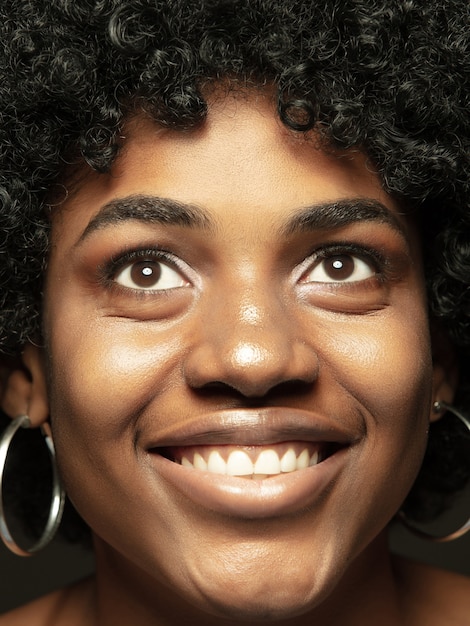 Close-up portret van jonge en emotionele Afro-Amerikaanse vrouw. Zeer gedetailleerde foto van een vrouwelijk model met een verzorgde huid en een heldere gezichtsuitdrukking. Concept van menselijke emoties. Glimlachend.