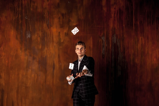 Close-up portret van jonge man met gokkaarten. Knappe jongen geeft over met kaart. Slimme handen van goochelaar
