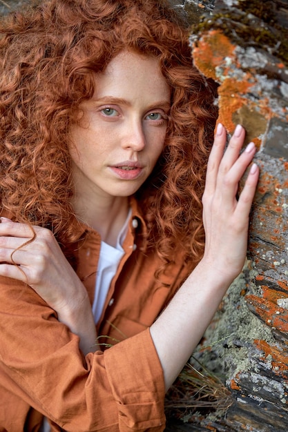 Close-up portret van jonge roodharige vrouw die zich voordeed op camera leunde op berg rots romantisch en dromerig...