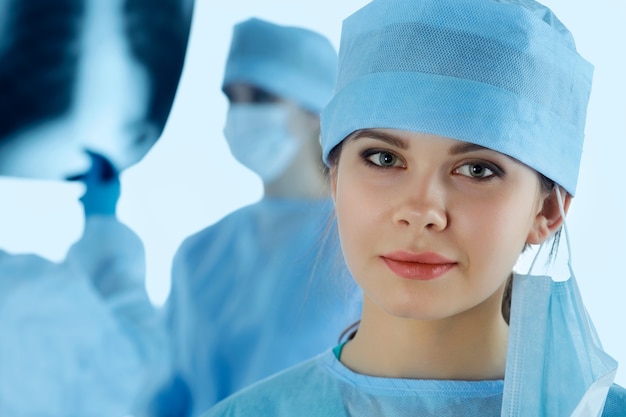 Close-up portret van jonge vrouwelijke chirurg arts omringd door haar team