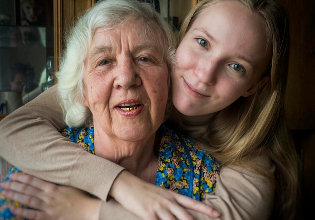 Foto close-up portret van kleindochter die grootmoeder omhelst terwijl ze thuis is