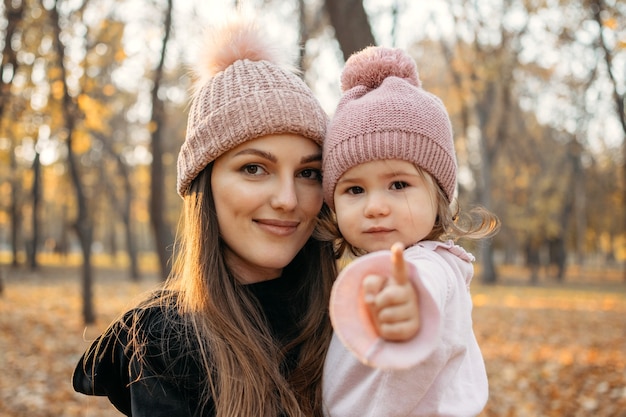 Close-up portret van moeder en peuter dochtertje in herfst park met kinderwagen gelukkige familie