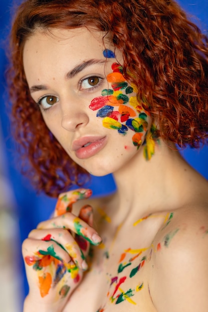 Foto close-up portret van rood krullend haired vrouw jonge vrolijke bevuild in verf. portret van een meisje met een creatief patroon op haar gezicht. conceptfotografie voor kunst- of vrouwenblog