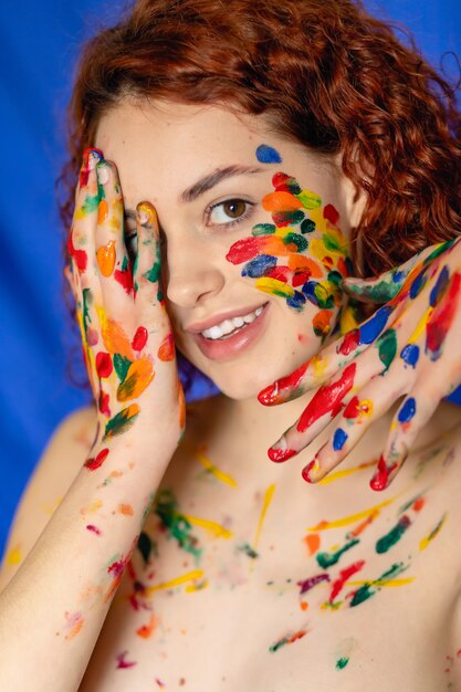 Close-up portret van rood krullend haired vrouw Jonge vrolijke bevuild in verf. Portret van een meisje met een creatief patroon op haar gezicht. Conceptfotografie voor kunst- of vrouwenblog