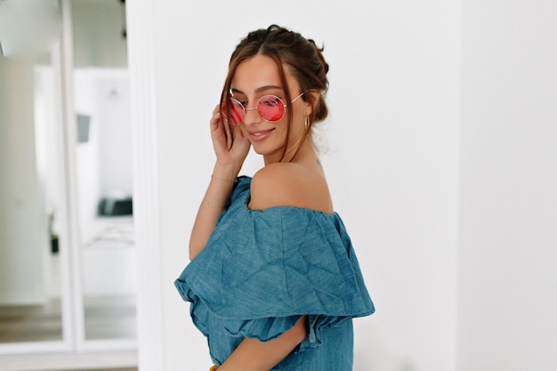 Close-up portret van schattige mooie vrouw met donker haar en gebruinde huid met jeans top en roze fashion bril
