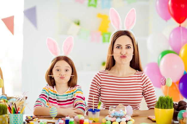 Close-up portret van twee mooie aantrekkelijke mooie komische kinderachtig vrolijke vrolijke meisjes kleine pre-tiener dochtertje dragen bunny oren houden potlood pruillip lippen in wit licht interieur huis