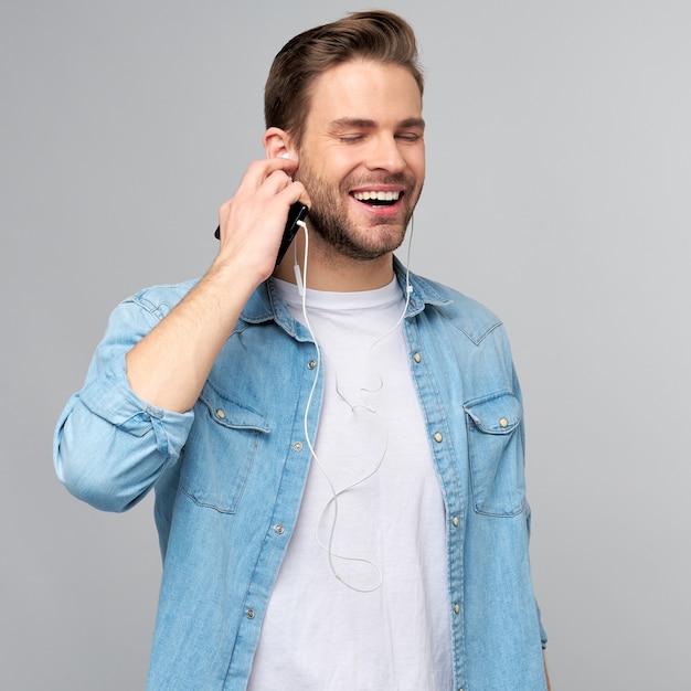 Close-up portret van vrolijke jonge man genieten van het luisteren naar muziek in casual jeans outfit