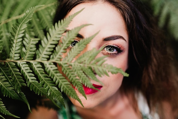 Foto close-up portret van vrouw door groene bladeren