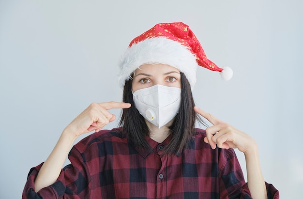 Close-up portret van vrouw in medisch, wegwerpmasker en rode kerstmuts