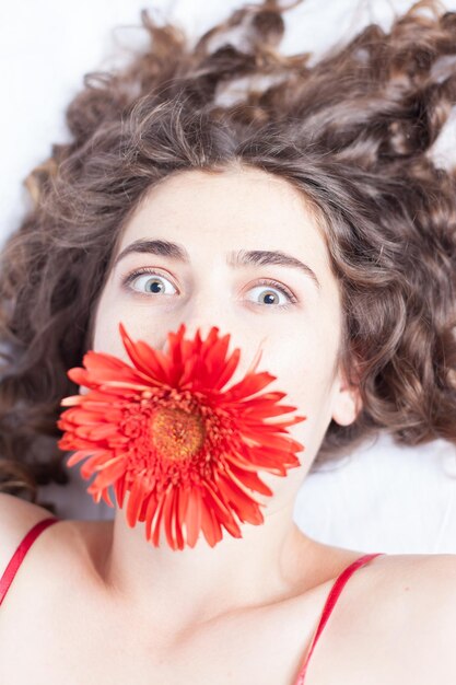 Foto close-up portret van vrouw met rode bloem op het gezicht