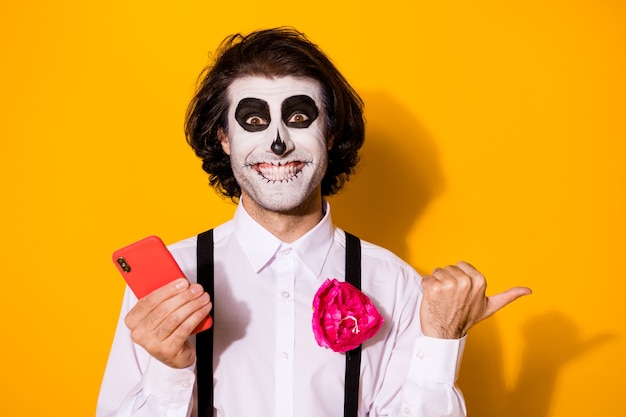 Close-up portret van zijn aardige knappe griezelige, vrolijke, blije kerel die gadget-app 5g gebruikt die kopieerruimte advertentie calavera geïsoleerd helder levendig glanst levendige gele kleur achtergrond demonstreert