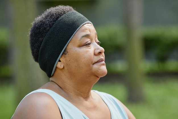 Close-up portret van zwarte vrouw met overgewicht die buitenshuis traint en wegkijkt naar kopieerruimte
