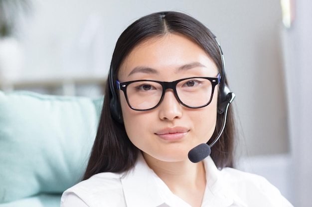 Close-up portretfoto van Aziatische vrouwelijke callcentermedewerker en technische ondersteuningsmedewerker die naar de camera kijkt