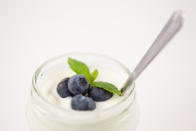 Close up of a pot of yoghurt with blueberries and fresh mint