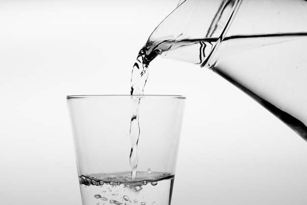 Close up pouring drinking water into glass