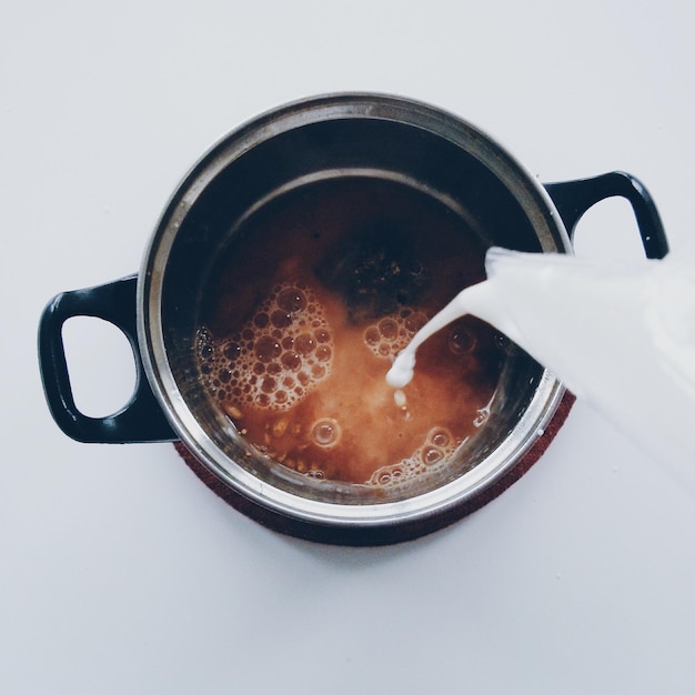 Foto prossimo piano del versamento del latte nella teiera