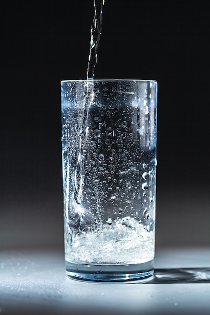 Close up pouring purified fresh drink water from the bottle on table