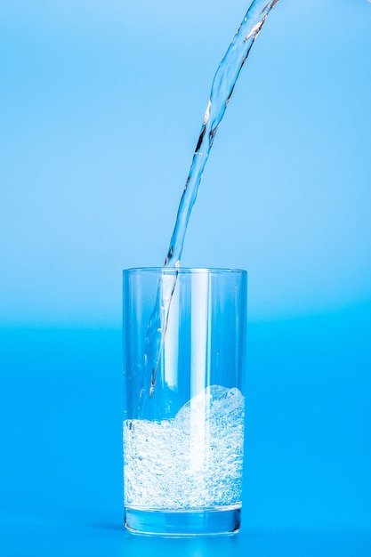 Close up pouring purified fresh drink water from the bottle on\
table