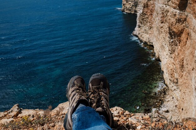 Close up pov of hiking boots of an independent male traveler on\
top of a mountain looking at the view