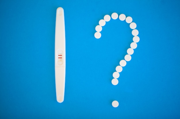 Chiuda su del concetto del controllo delle nascite delle pillole del contraccettivo e del test di gravidanza sul blu