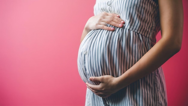 Close up of pregnant belly on pink background