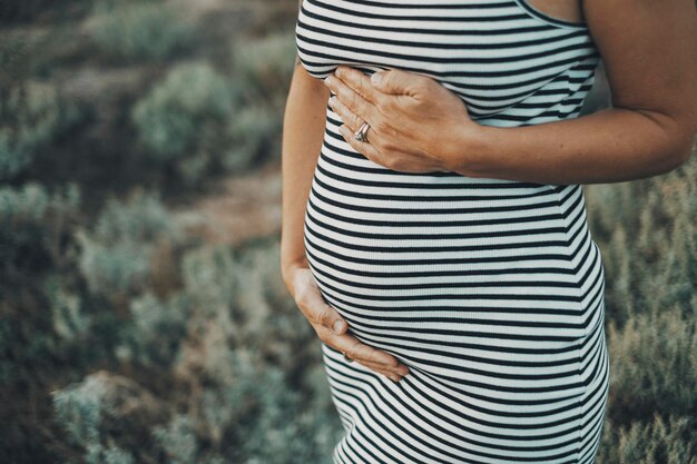 Close up of pregnant people. Mature lady 45 years old with pregnant belly in outdoor portrait. Future mommy newborn lifestyle. Adult woman waiting children.