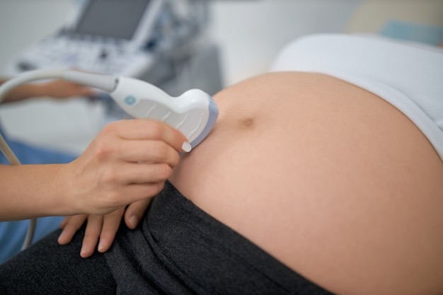 Close up of pregnant woman having ultrasound scanning at medical clinic