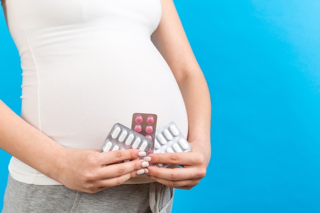 Close up of pregnant woman holding maternal supplements