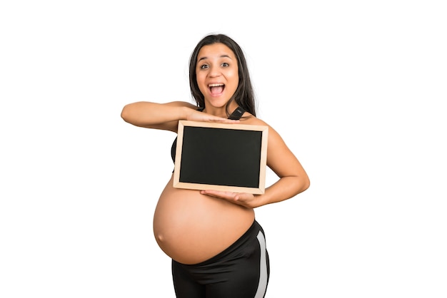 Close-up of pregnant woman holding and showing something on chalkboard. Pregnancy, motherhood and promotion ad concept.