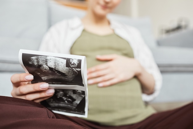 Primo piano di una donna incinta che tiene tra le mani l'ecografia del suo bambino