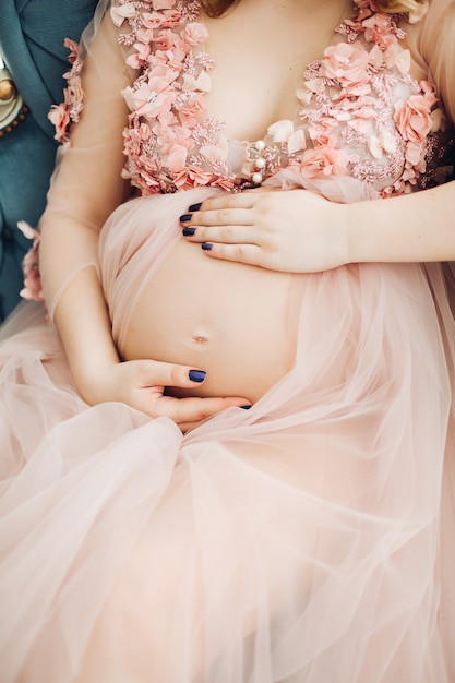 Close up of pregnant woman in long dress touching belly