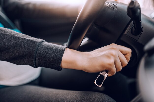 Foto chiuda in su della donna incinta che inizia l'automobile.