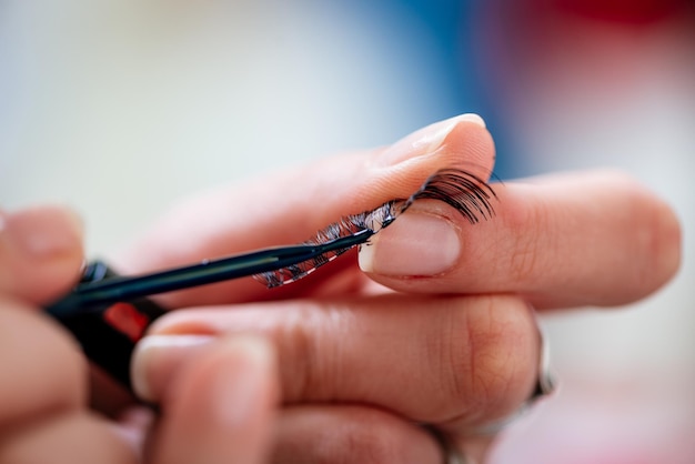 Close-up of a preparing false eyelashes with a cosmetic glue for applying to model.