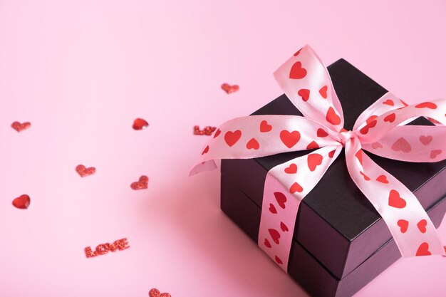 Close up present gift box with bow on pink background Valentines Day gift and hearts