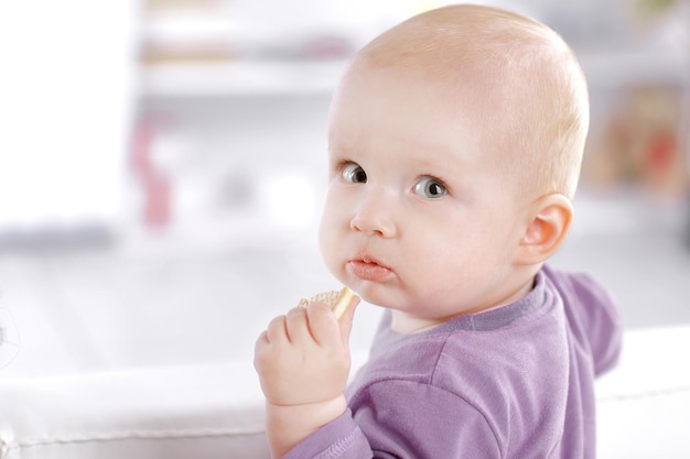 Крупным планом симпатичный ребенок ест печенье и смотрит в камеру