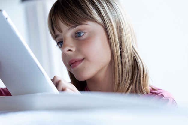 Primo piano di una bambina abbastanza concentrata che usa la sua tavoletta digitale a casa.