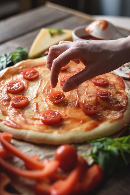 Close up process of cooking pizza with selective focus on the hand.