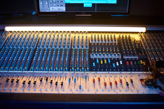 Close-up of professional audio mixing console with computer in\
digital recording studio