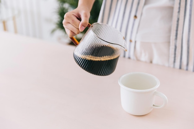 사진 흰색 머그에 갓 내린 드립 커피를 붓는 전문 바리스타 손을 닫습니다. 커피 대체 방법 준비