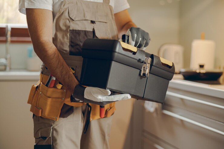 Photo close up of professional handyman standing on home kitchen and holding his tool bag