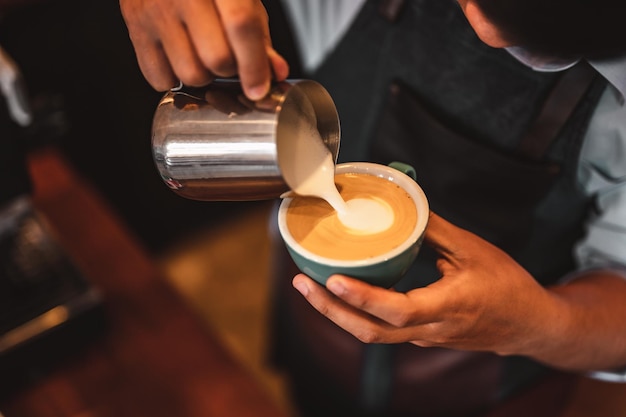 Close-up of professionally extracting coffee by barista with a pouring steamed milk into coffee cup making beautiful latte art. coffee, extraction, deep, cup, art, barista concept.