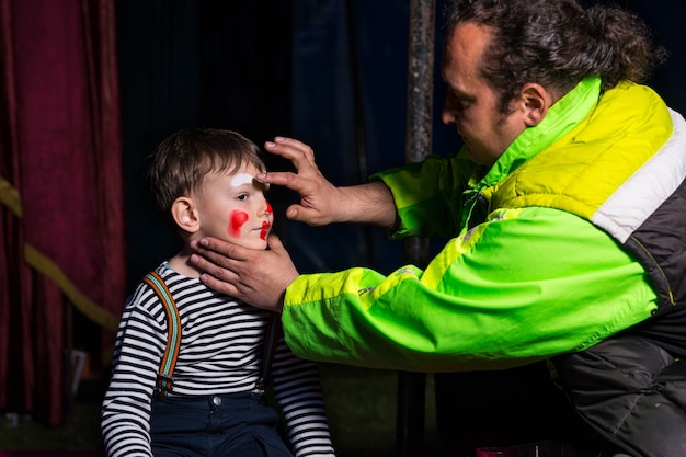 Foto close-up profiel van man witte clown make-up toe te passen op jongens gezicht