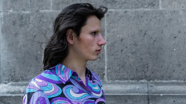 Close-up of a profile of a non-binary person with a brick background.